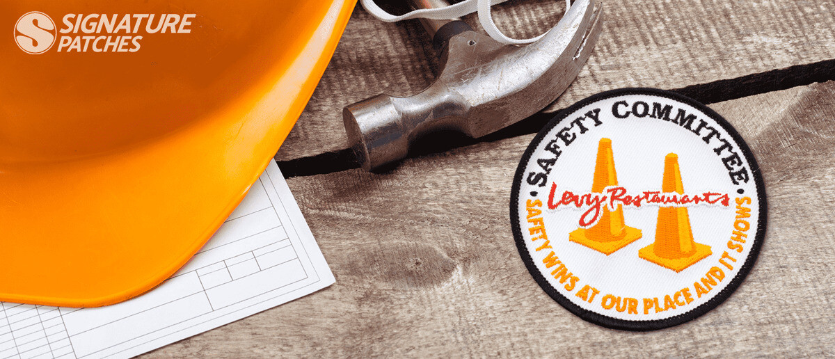 Safety Committee patch with orange traffic cones next to hard hat and tools
