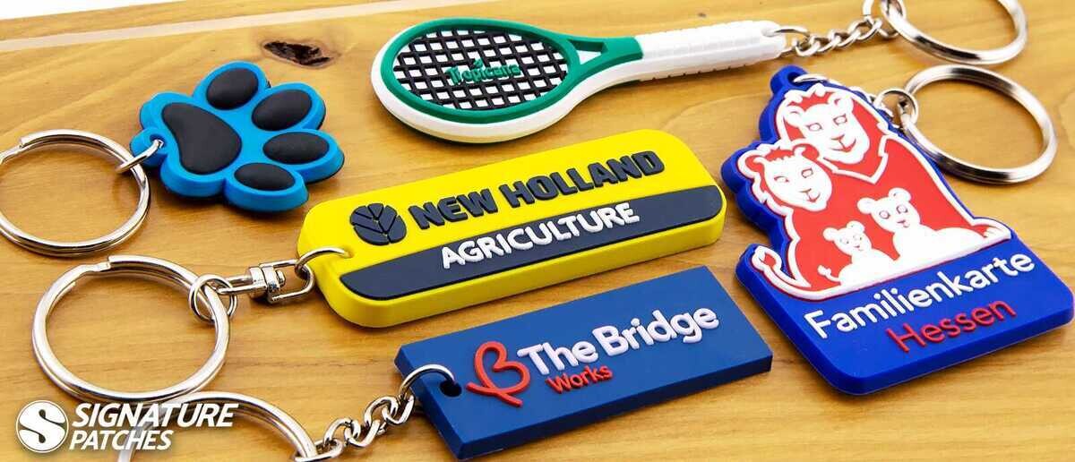 Custom PVC keychains in various shapes including paw print, tennis racket, and company logos