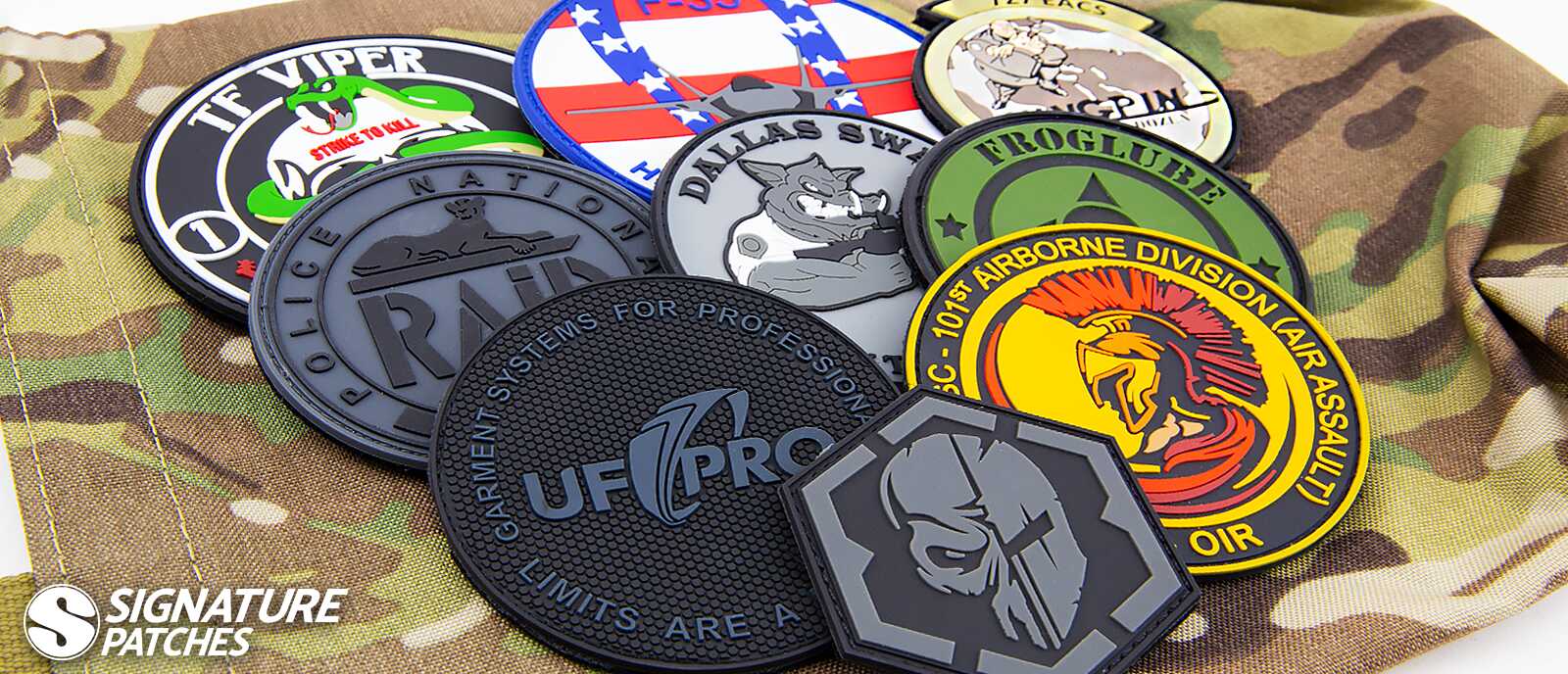Collection of custom PVC morale patches displayed on camouflage fabric, featuring military and law enforcement designs